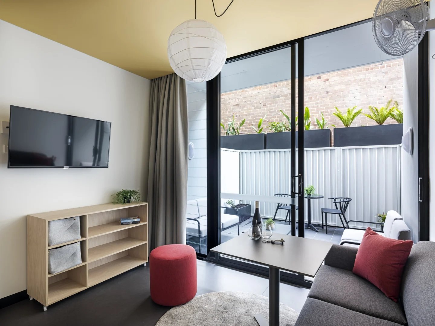 TV shelf red ottoman grey couch living area at UKO Newtown in Sydney Student Accommodation