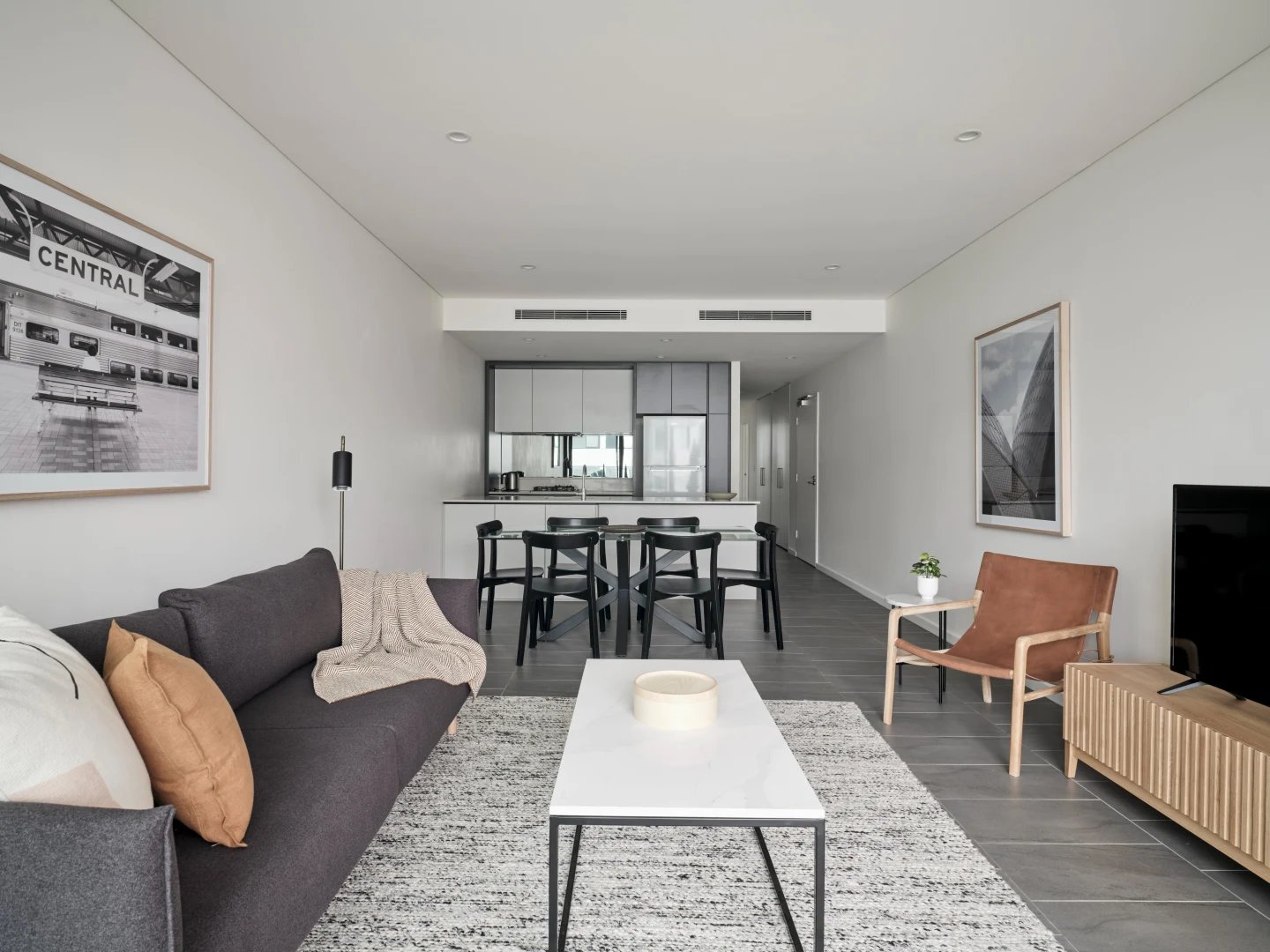 Sofa coffee table dining chairs kitchen living room at UKO Camperdown in Sydney Student Accommodation