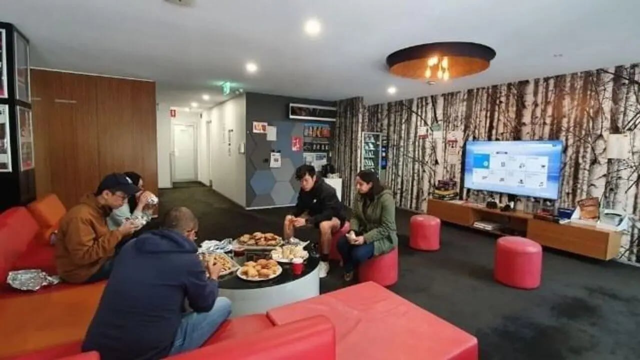 Students eating food on red couches television living room at Student Living D1 in Melbourne Student Accommodation