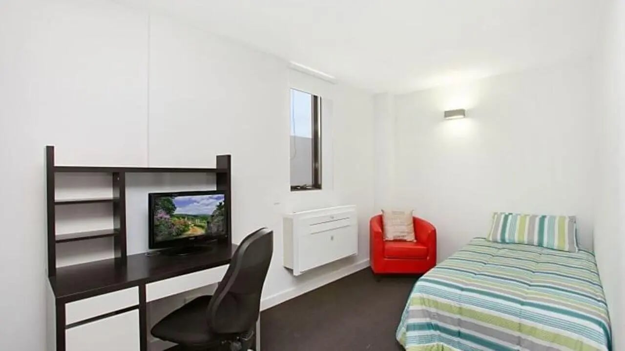 Desk chair monitor red armchair striped bed bedroom at Student Living on Raleigh in Melbourne Student Accommodation