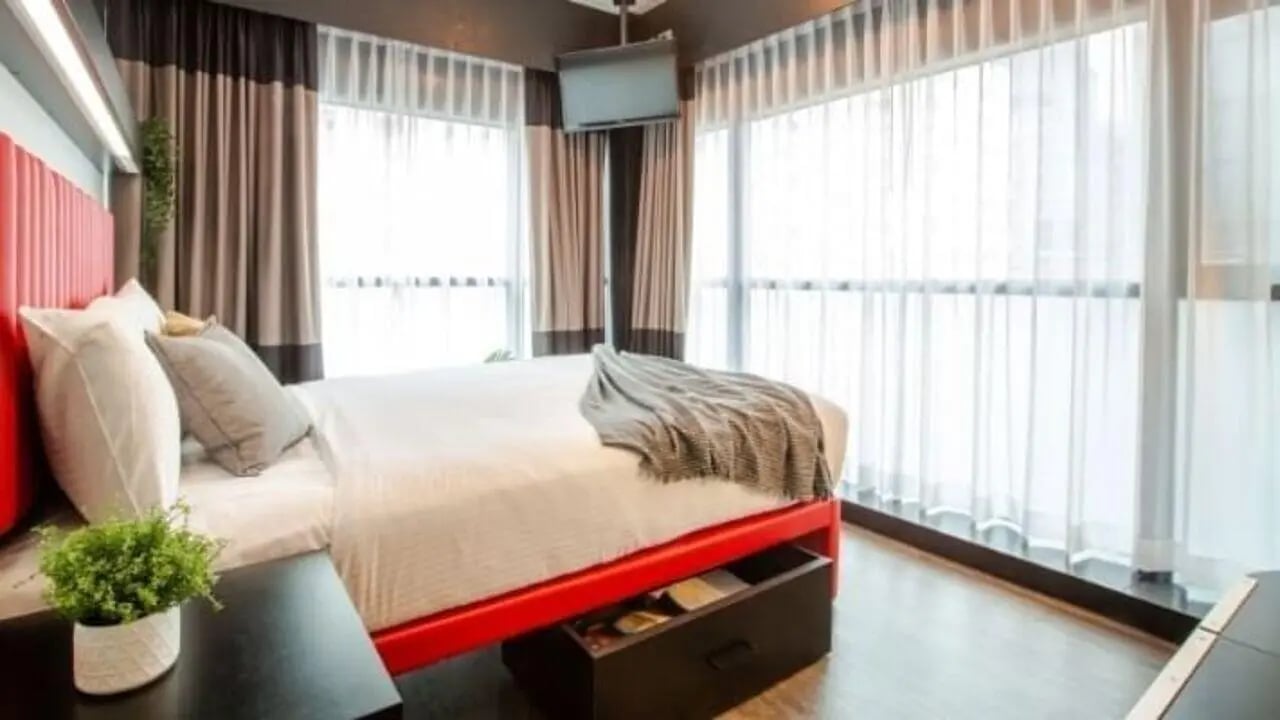 Bed with red frame white pillows grey throw bedroom at UniLodge Carlton in Melbourne Student Accommodation