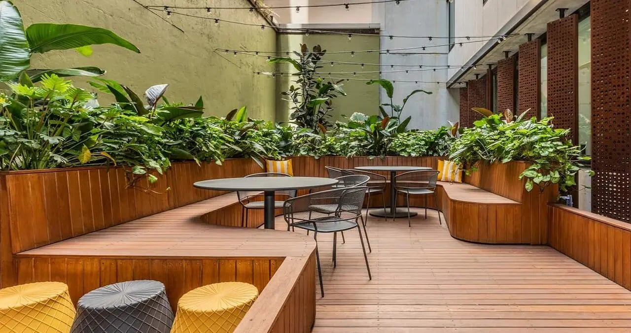Wooden benches tables chairs and planters outdoor seating area at Iglu Central in Sydney Student Accommodation