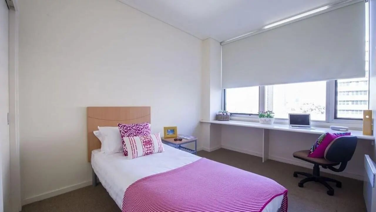 Bed with pink blanket and desk Bedroom at Student Living - 570 Lygon in Melbourne Student Accommodation