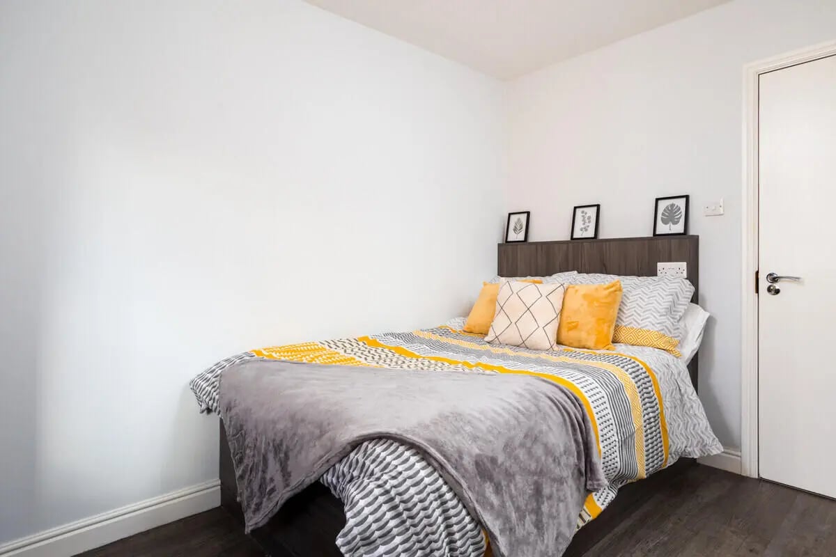 Bed with yellow pillows and framed art bedroom at Royal Park Road in Leeds Student Accommodation