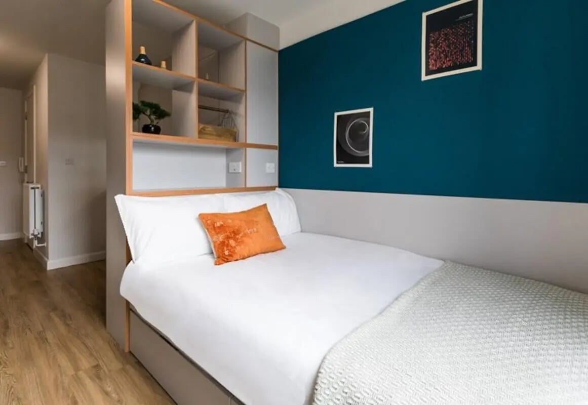 Bed with orange pillow shelf unit artwork Bedroom at Stoneworks in Brighton Student Accommodation