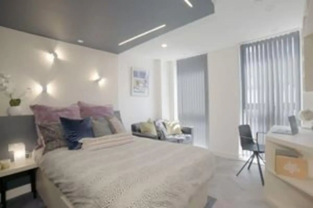 Bed with pillows couch desk chair and blinds bedroom at The Orchard in Leicester Student Accommodation