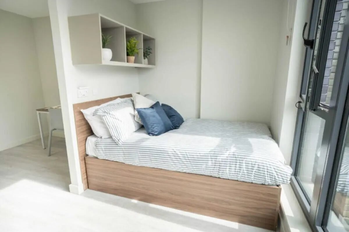 Bed with pillows shelves plants desk and chair bedroom at The Toybox in Birmingham Student Accommodation