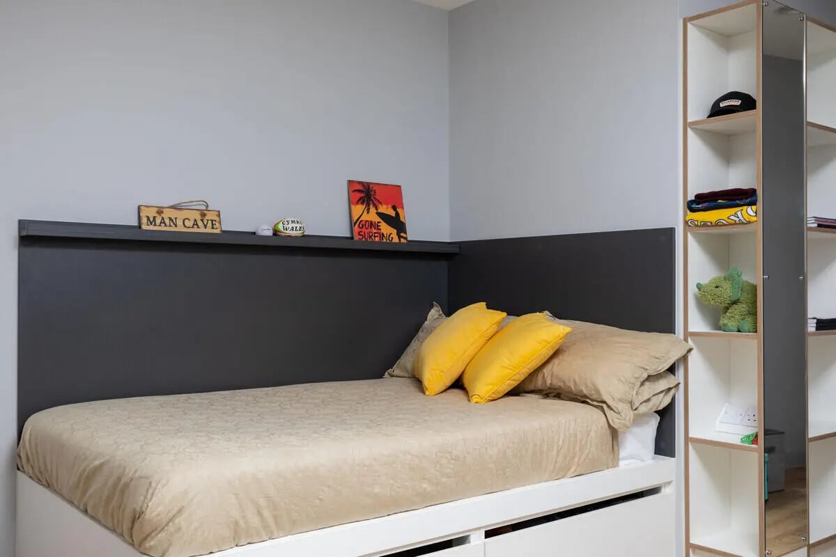 Bed yellow pillows shelf stuffed animal bedroom at West Wing in Cardiff Student Accommodation