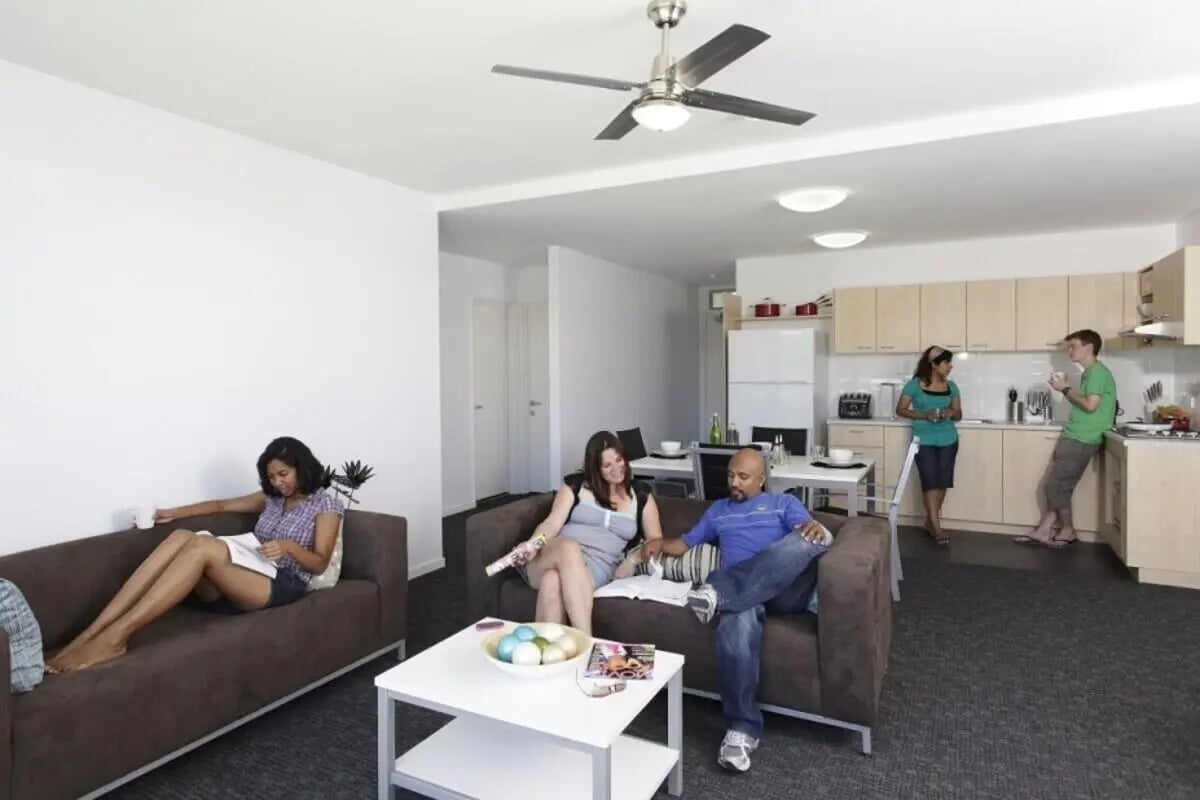 People relaxing in a common area with kitchen living room at Murdoch University Village in Perth Student Accommodation