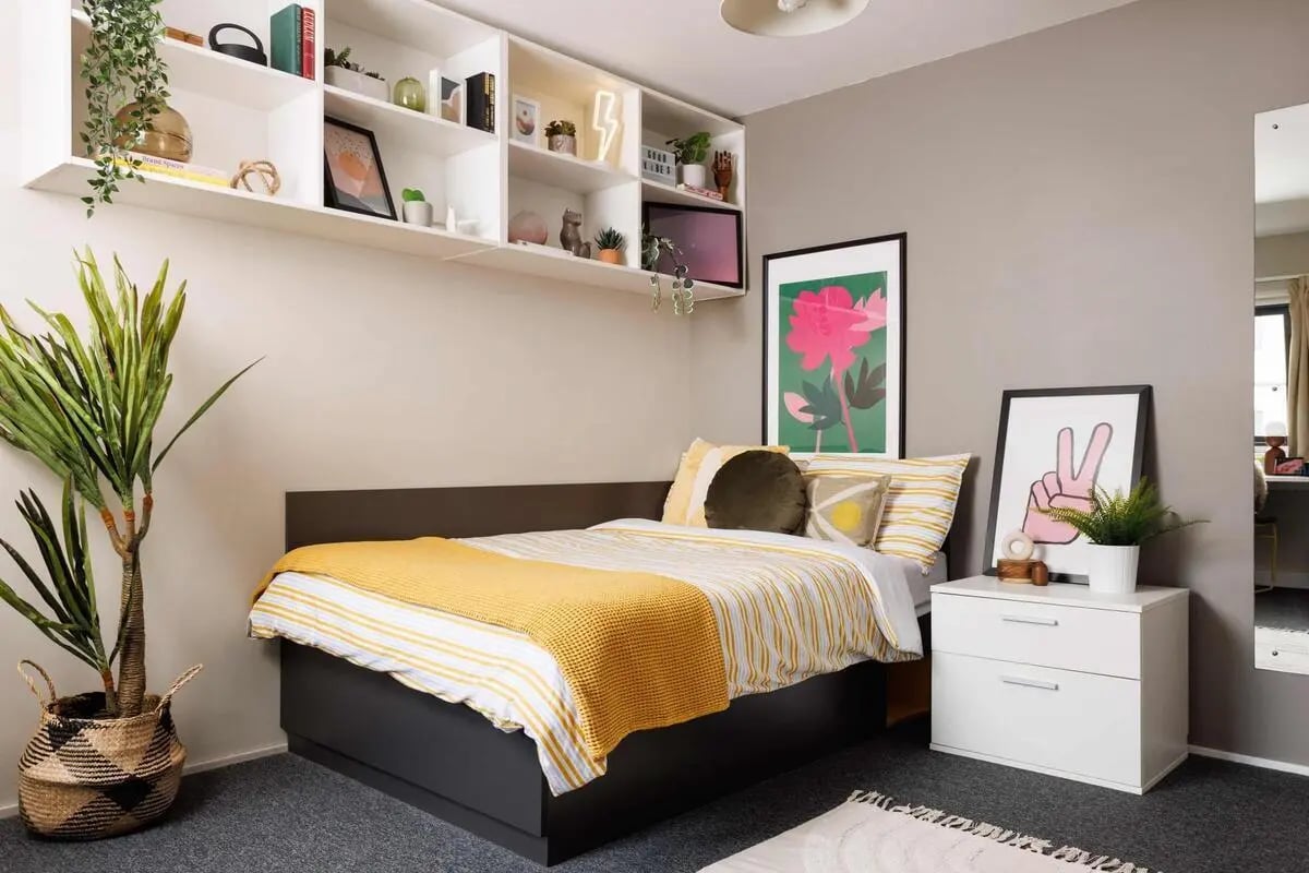 Bed with yellow blanket shelves plants and dresser bedroom at Exchange Works in Sheffield Student Accommodation