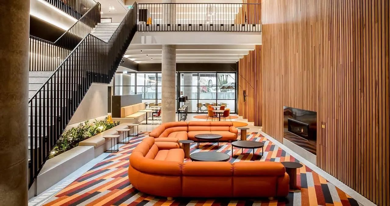Orange sectional sofa fireplace staircase lounge area at Iglu South Yarra in Melbourne Student Accommodation