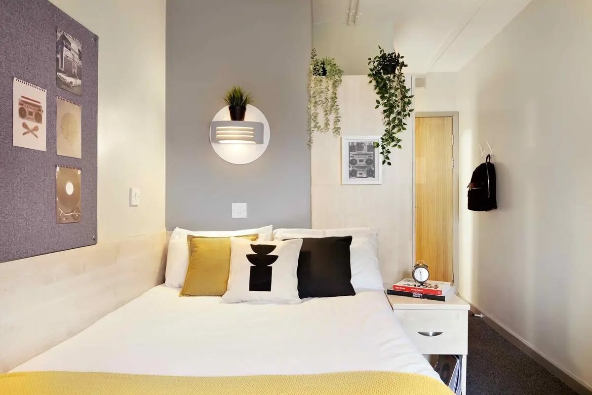 Bed with pillows artwork and plants bedroom at St Thomas Court in Plymouth Student Accommodation