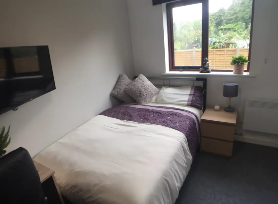 Bed with purple duvet bedside table TV bedroom at Kingfisher Halls in Loughborough Student Accommodation