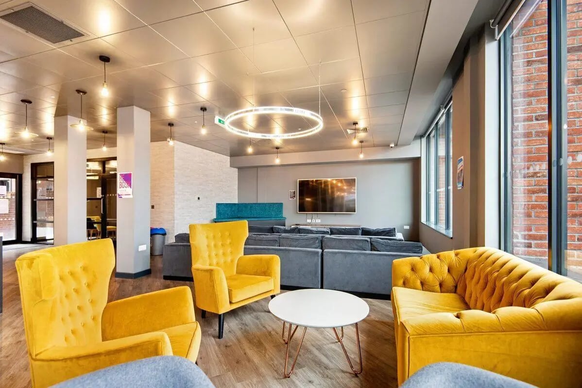 Yellow chairs grey sofas television lounge area at Coppergate Swansea in Swansea Student Accommodation