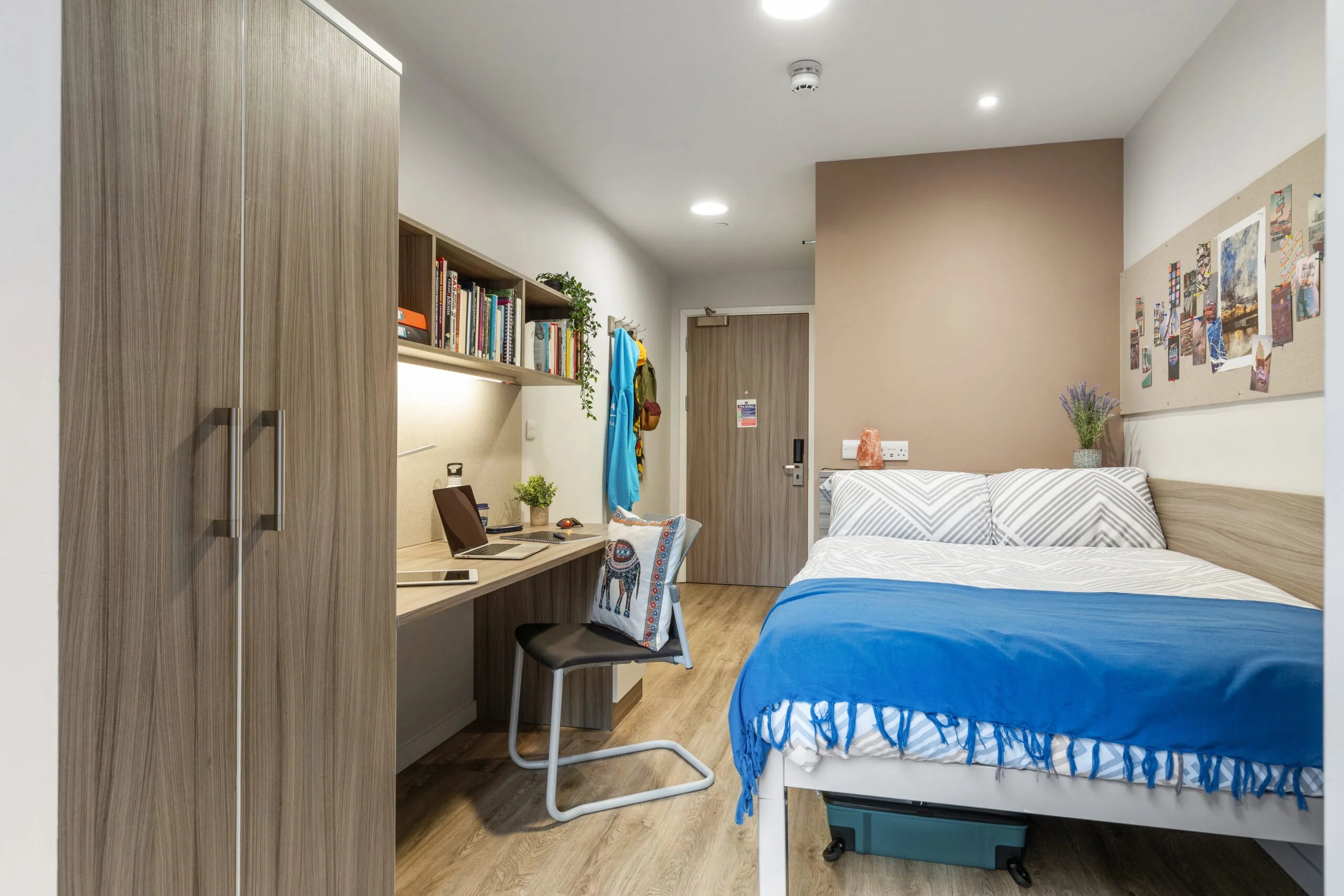 Wardrobe desk chair bed with blue throw Bedroom at Kaplan Living Brighton in Brighton Student Accommodation