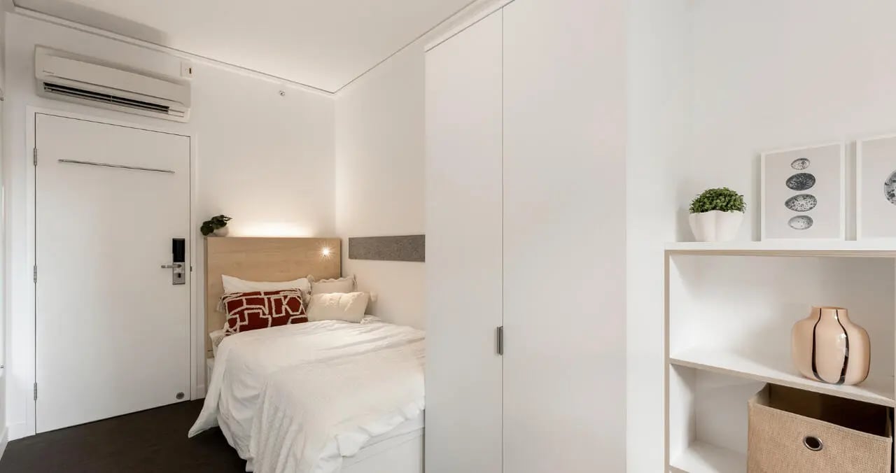 Bed with white linens air conditioner and door Bedroom at Iglu Brisbane City in Brisbane Student Accommodation