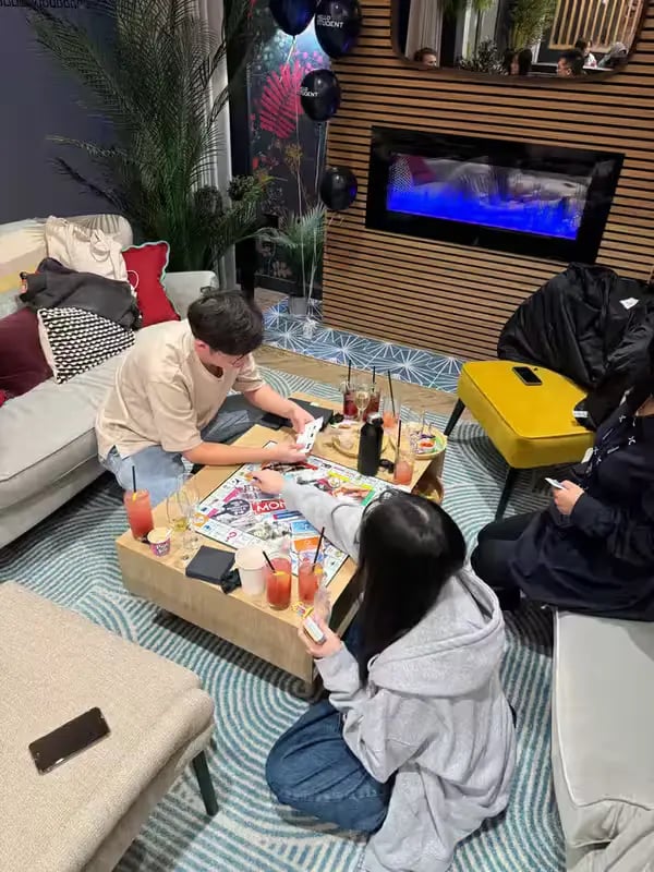 Students playing board game on couch living room at St Peter Studios in Aberdeen Student Accommodation