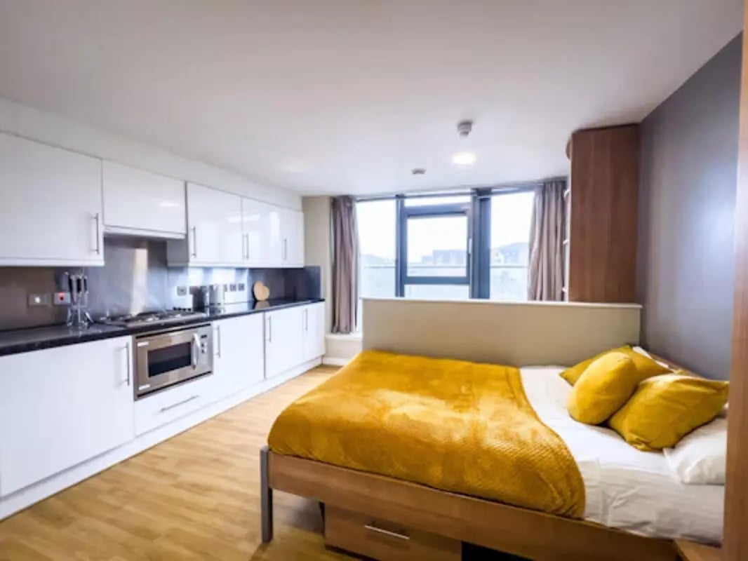 Bed kitchen white cabinets wood floor study area at Lady Nicolson Court in Edinburgh Student Accommodation