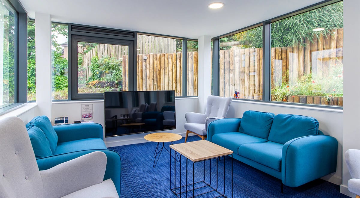 Blue sofas grey chairs television with garden view living room at Goods Corner in Edinburgh Student Accommodation