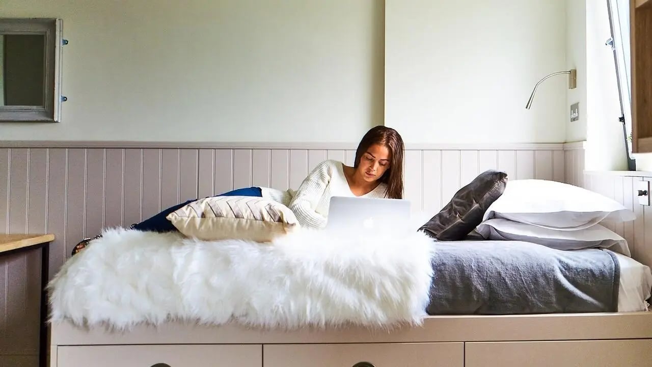 Woman on bed with laptop bedroom at Canvas The Parade in Cardiff Student Accommodation