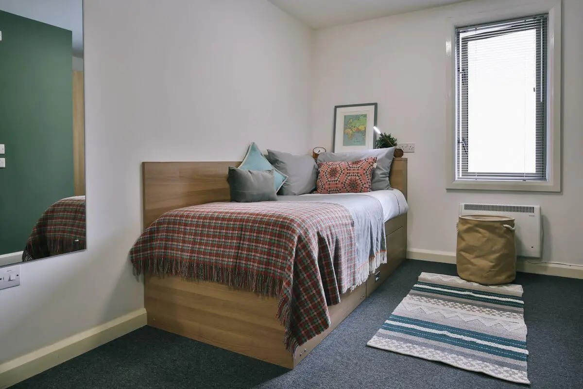Bed with plaid blanket and pillows study area at Victoria Court in Lancaster Student Accommodation