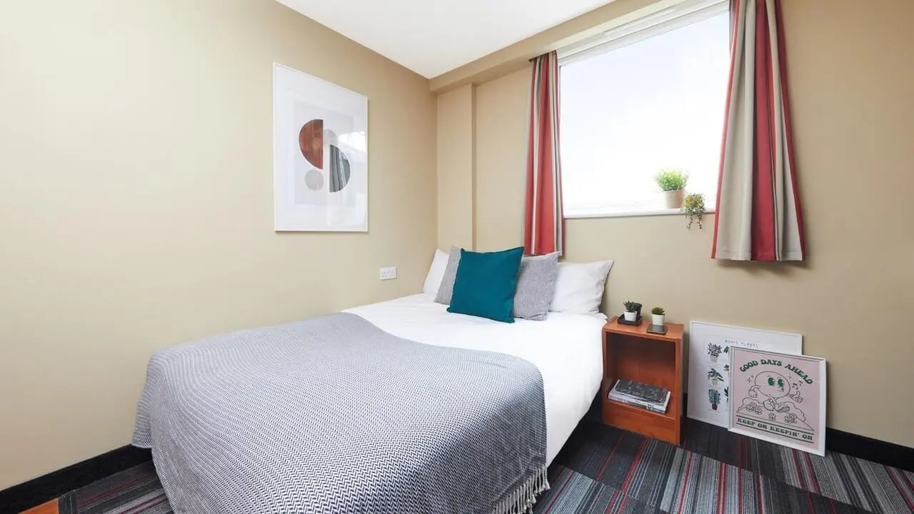 Bed with teal pillows and art bedroom at Market Way in Coventry Student Accommodation