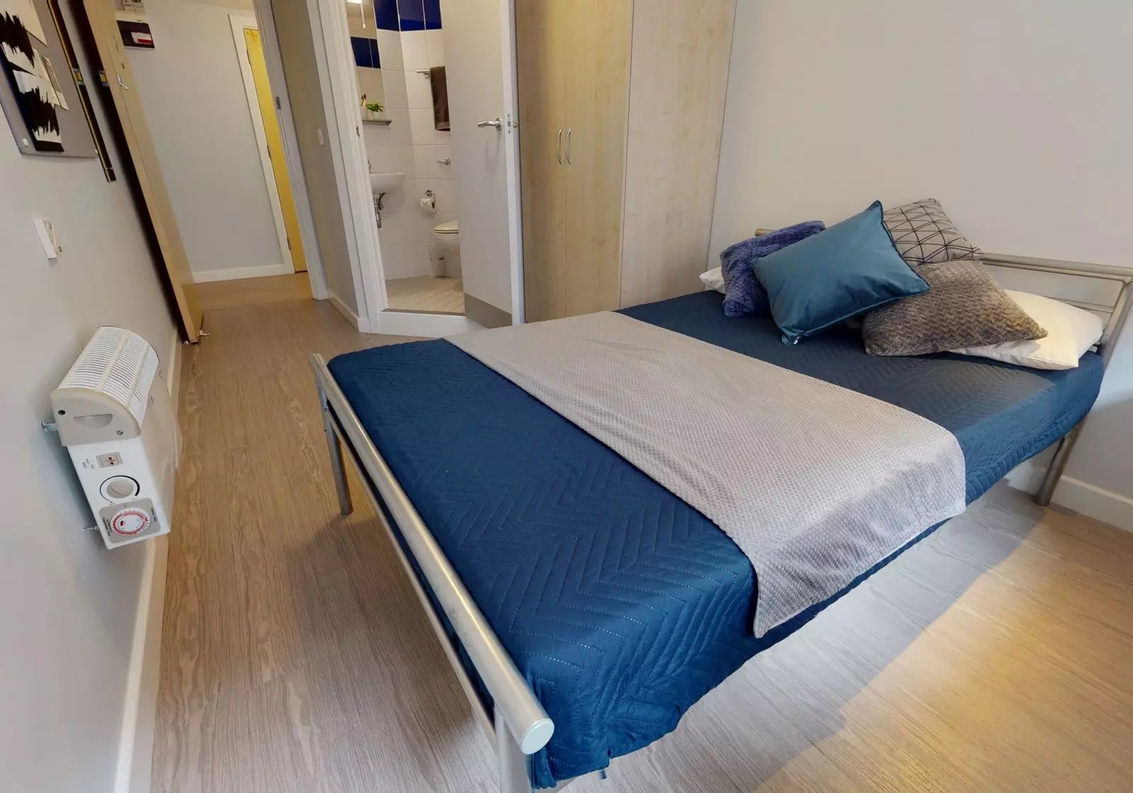 Bed with blue quilt and pillows wardrobe and bathroom Bedroom at iQ Fenton House in Sheffield Student Accommodation