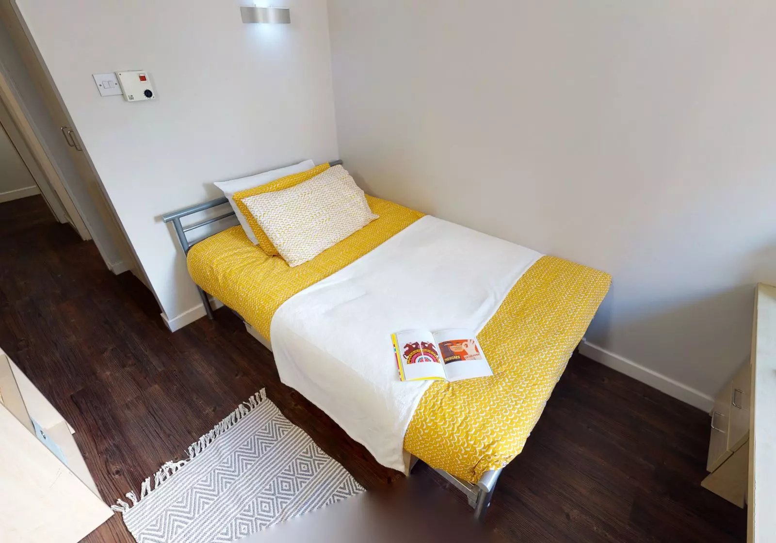 Bed with yellow bedding open book bedside rug bedroom at iQ Great Newton House in Liverpool Student Accommodation
