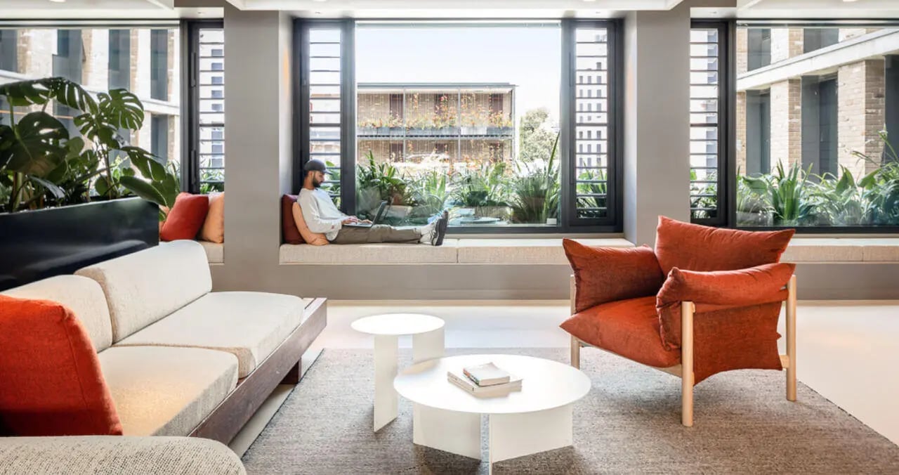 Sofa armchair coffee tables and plants living room at Iglu Summer Hill in Sydney Student Accommodation