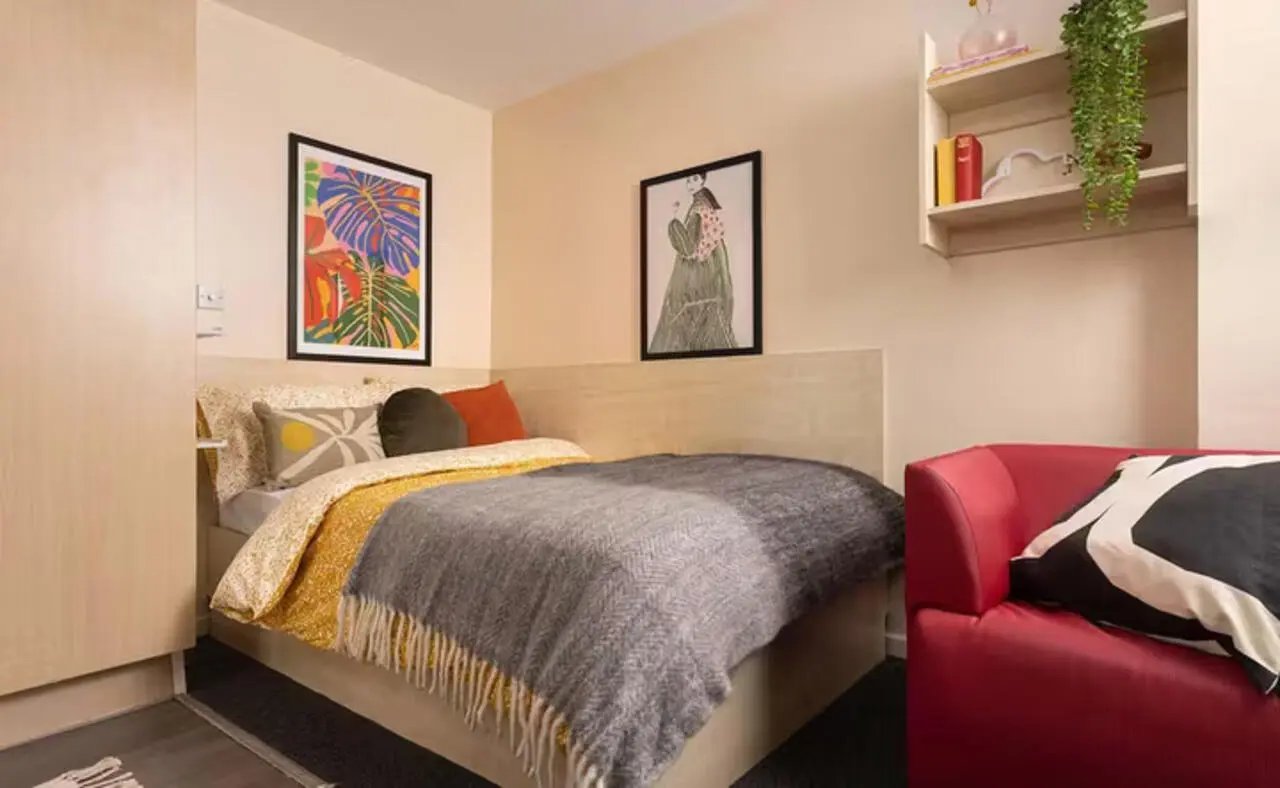 Bed pillows artwork red chair bedroom at The Plaza in Leeds Student Accommodation
