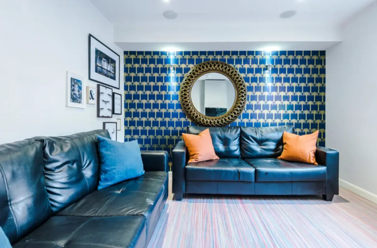 Black sofas framed art blue patterned wallpaper living room at 9 Queen Anne Street in Stoke-On-Trent Student Accommodation