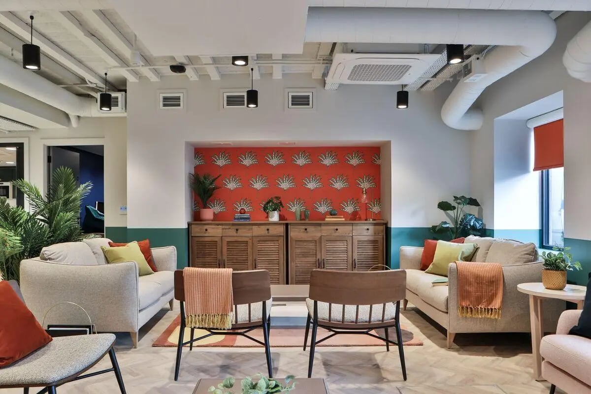 Sofas cabinet chairs plants patterned wall living room at St Mark's Court in Leeds Student Accommodation