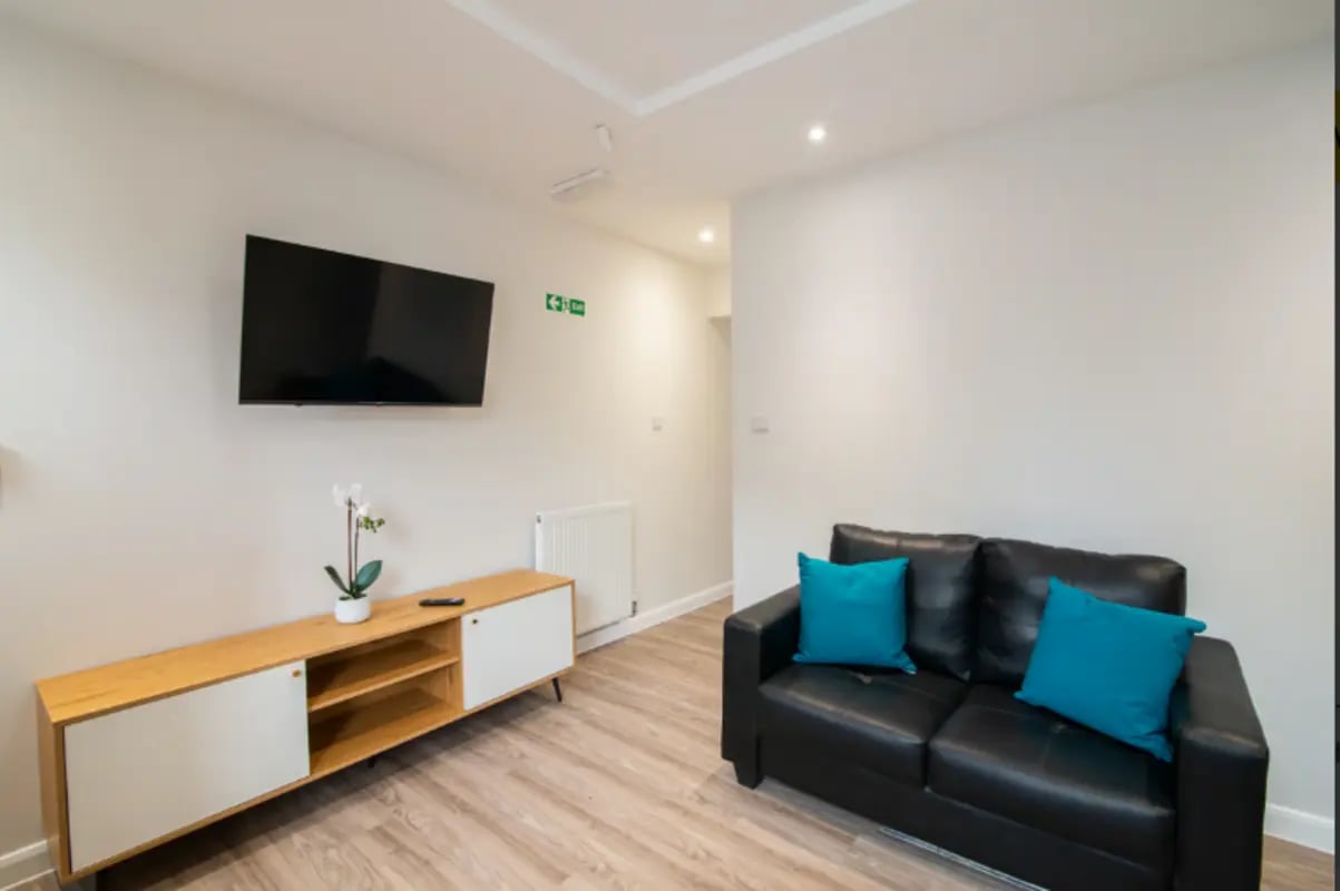 Black sofa two teal cushions TV and media unit living room at 18 Cauldon Road in Stoke-On-Trent Student Accommodation