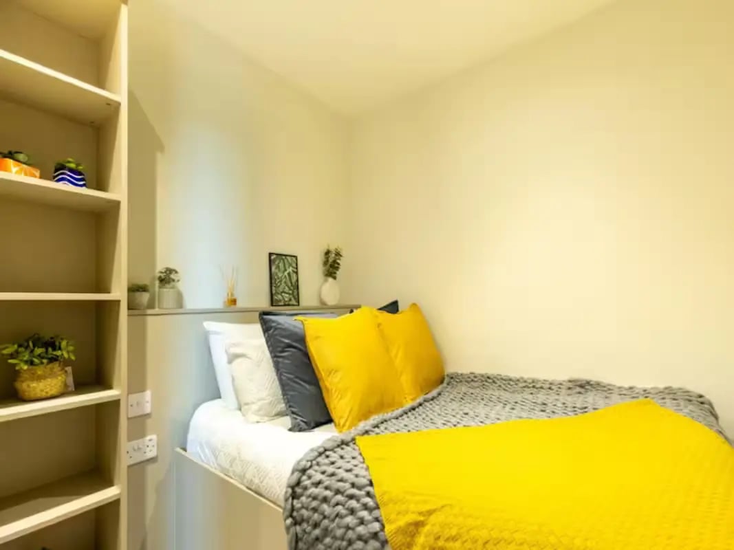 Bed with yellow pillows and grey blanket bedroom at Redvers Tower in Sheffield Student Accommodation