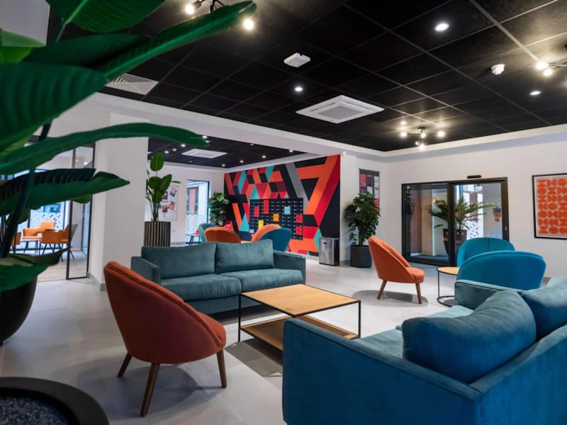 Lounge with teal sofas and orange chairs communal area at Steelworks in Sheffield Student Accommodation