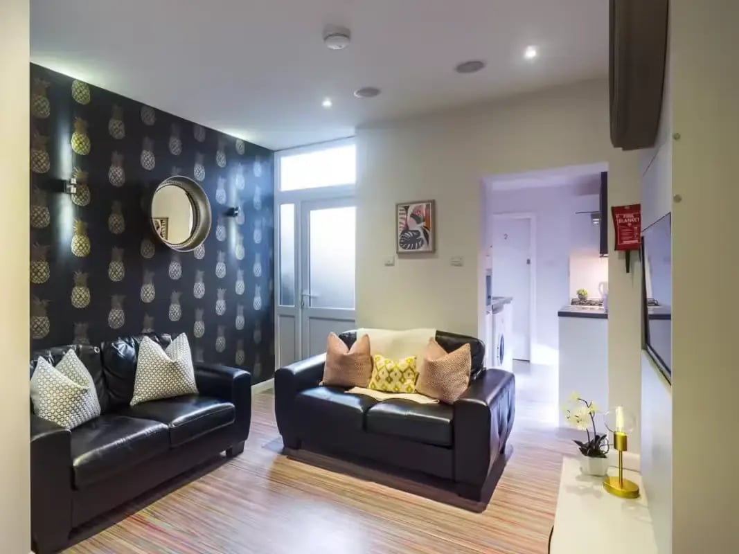 Two black sofas pineapple wallpaper living room at 30 Watford Street in Stoke-On-Trent Student Accommodation