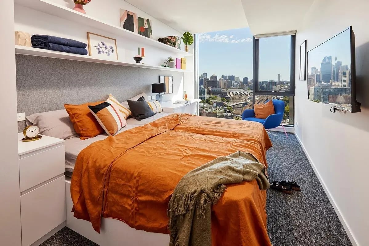 Orange bed desk blue chair cityscape bedroom at Scape Redfern in Sydney Student Accommodation