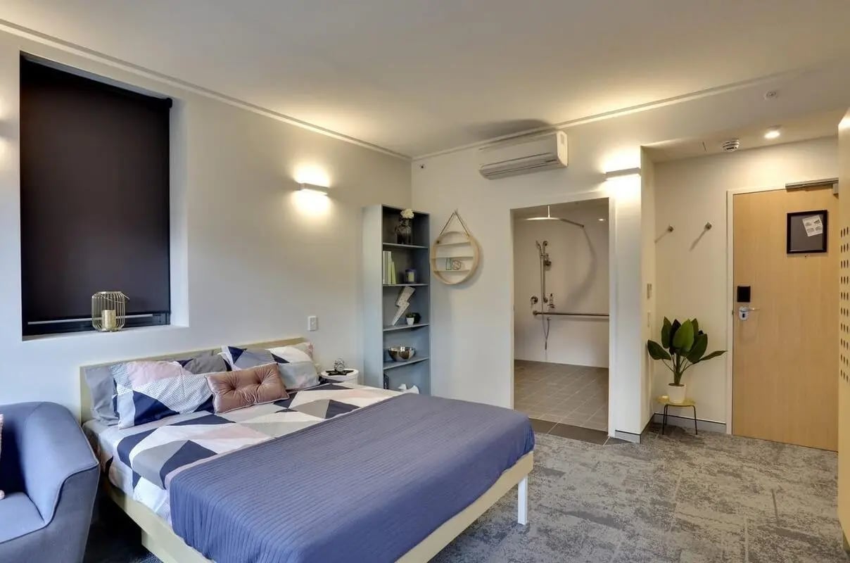 Bed patterned pillows shelf and shower room bedroom at Scape Darling House in Sydney Student Accommodation