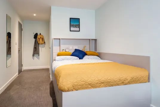 Bed with yellow and blue pillows headboard bedroom at Carrick View in Falmouth Student Accommodation