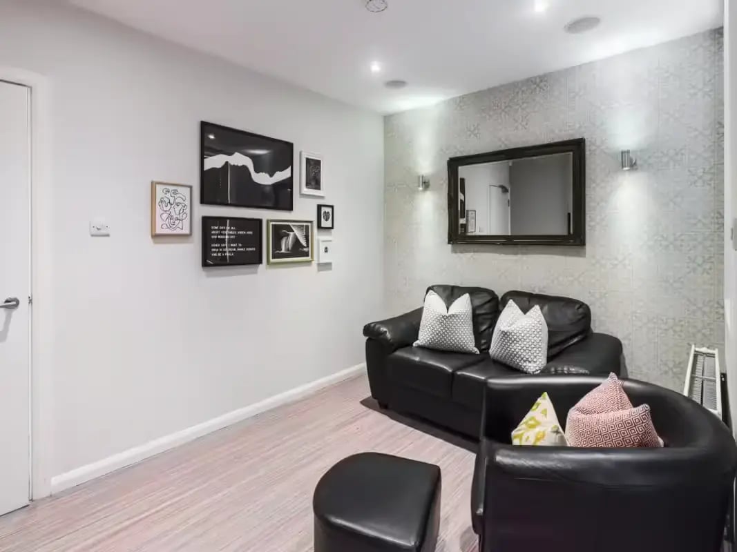 Black couches artwork mirror and ottoman living room at 6 Cauldon Road in Stoke-On-Trent Student Accommodation