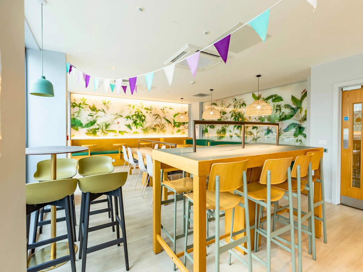 High table with chairs plant wall bunting communal area at Straits Meadows in Edinburgh Student Accommodation