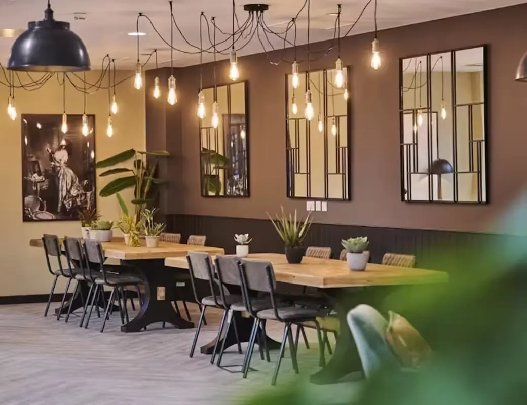 Dining tables with chairs plant decor living room at York House in Nottingham Student Accommodation