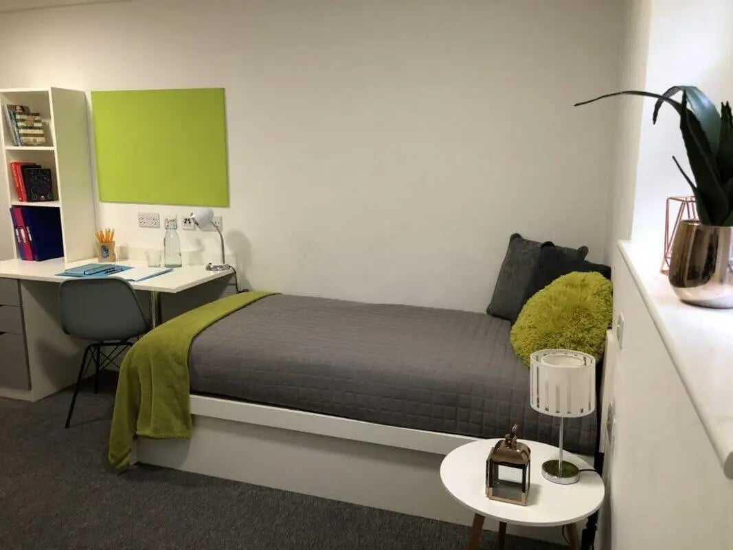 Bed desk chair bookshelf and green board bedroom at Tudor Studios in Leicester Student Accommodation