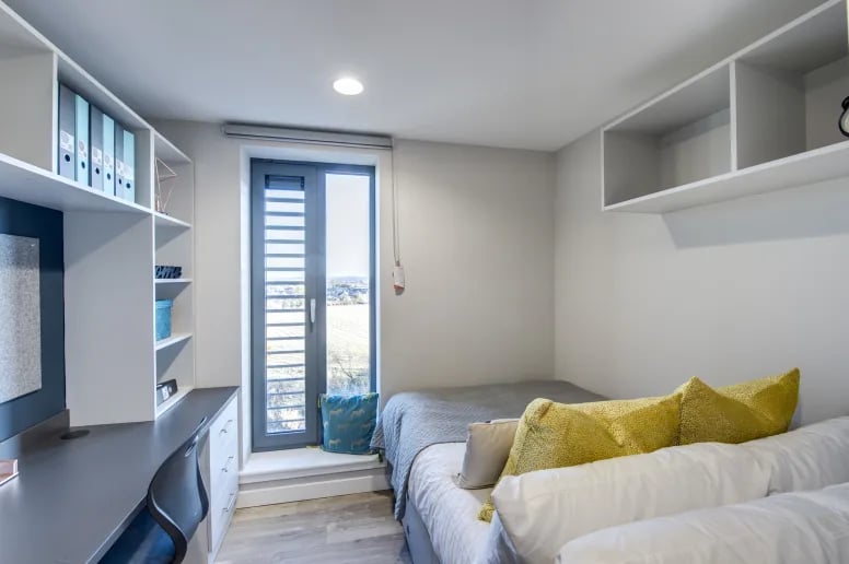 Desk shelves bed with yellow pillows bedroom at Riverside Quay in Stirling Student Accommodation