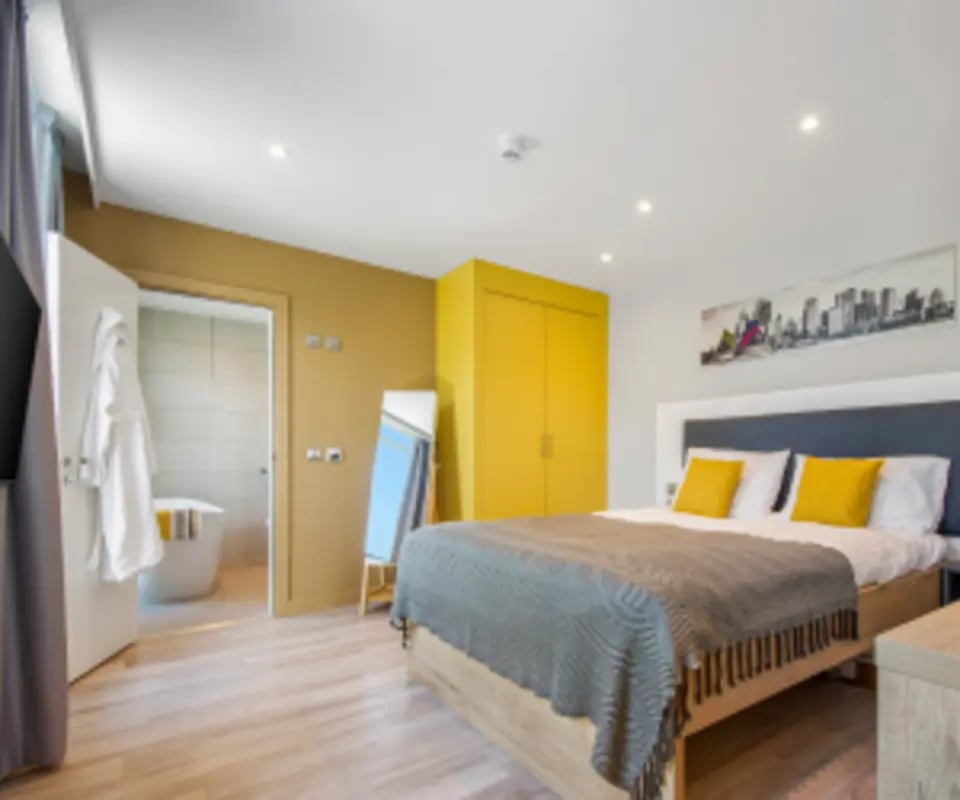 Bed with yellow pillows mirror open bathroom bedroom at Gravity in Lincoln Student Accommodation