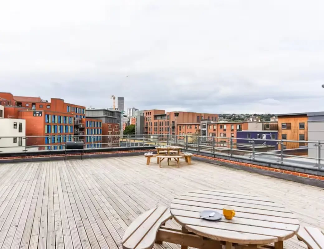 Wooden deck picnic tables with city buildings exterior at Page Apartments @ Central Place in Sheffield Student Accommodation