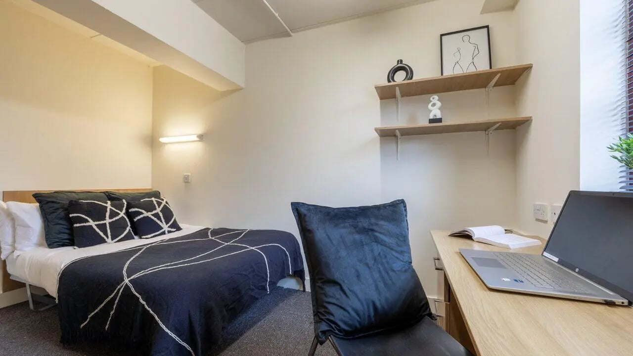 Bed with dark duvet and patterned pillows desk study area at Manchester Student Village in Manchester Student Accommodation