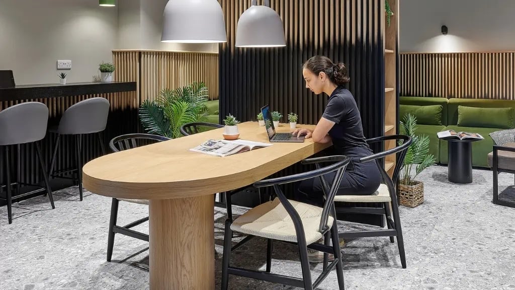Woman working laptop at communal study table common area at The Helix in London Student Accommodation