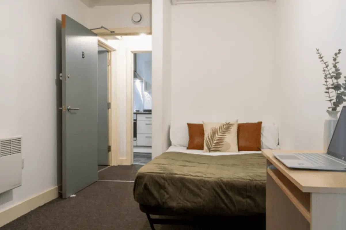 Bed with pillows desk with laptop bedroom study area at The Grafton in Manchester Student Accommodation