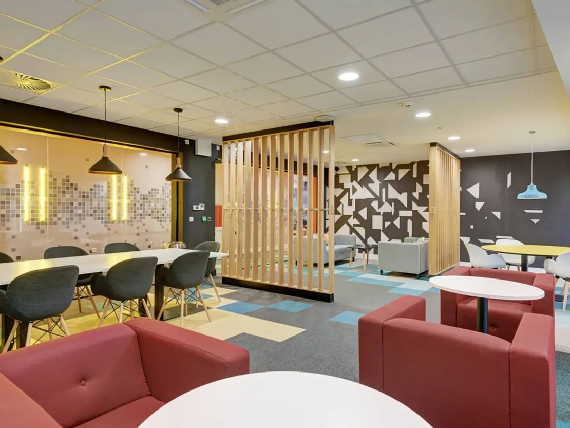 Modern lounge with red sofas white tables study area at New Bridewell in Bristol Student Accommodation